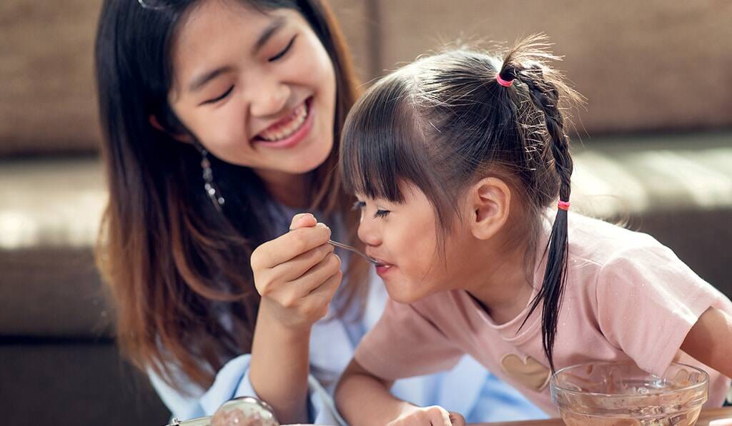 woman feeding her cute daughter