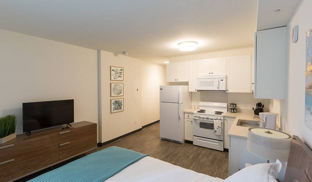 Studio apartment shows kitchen and bed