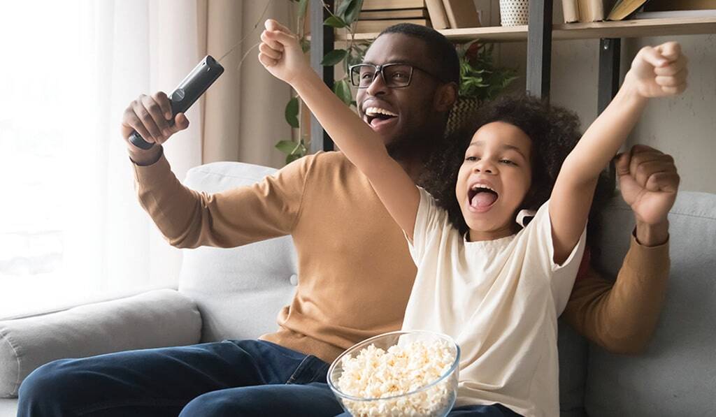 faher and child cheering on sofa